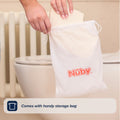 A hand places the Foldable Toilet Seat into a white Nuby drawstring bag by the toilet, highlighting its handy storage bag feature.