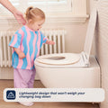 A young child stands by a toilet with the Foldable Toilet Seat, guided by an adult. Text on the image reads, Lightweight design that won’t weigh your changing bag down.