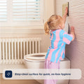 A young child in pastel clothes stands on tiptoe to push the flush near a Foldable Toilet Seat in a bright bathroom. Text reads: Easy-clean surface for quick, no-fuss hygiene.