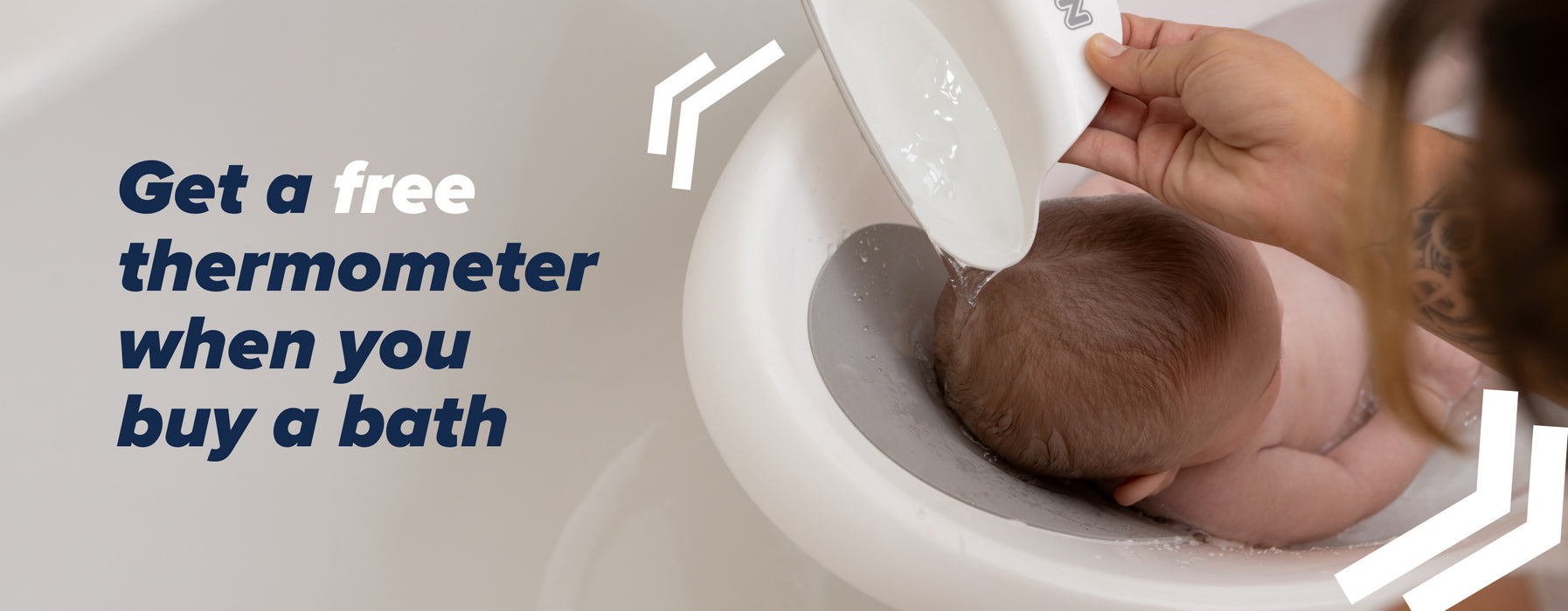 A baby sat in a Nuby bath, with water being poured over their head by their Mother.