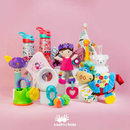 A vibrant assortment of baby essentials from the Nuby Baby Mystery Box—including a fairy doll, rattles, stuffed bear, water bottles, teething rings, and other soft toys—is artfully arranged against a pink background with the Cash for Kids logo at the bottom.