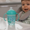 The Grip n Sip cup sat on a Baby's high chair table.