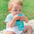 A young child drinking from their Incredible Gulp Dinosaur bottle for babies and young children by Nuby.