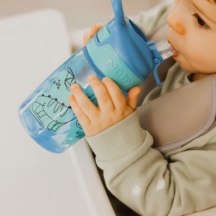 A young child drinking from their Incredible Gulp Dinosaur bottle for babies and young children by Nuby.