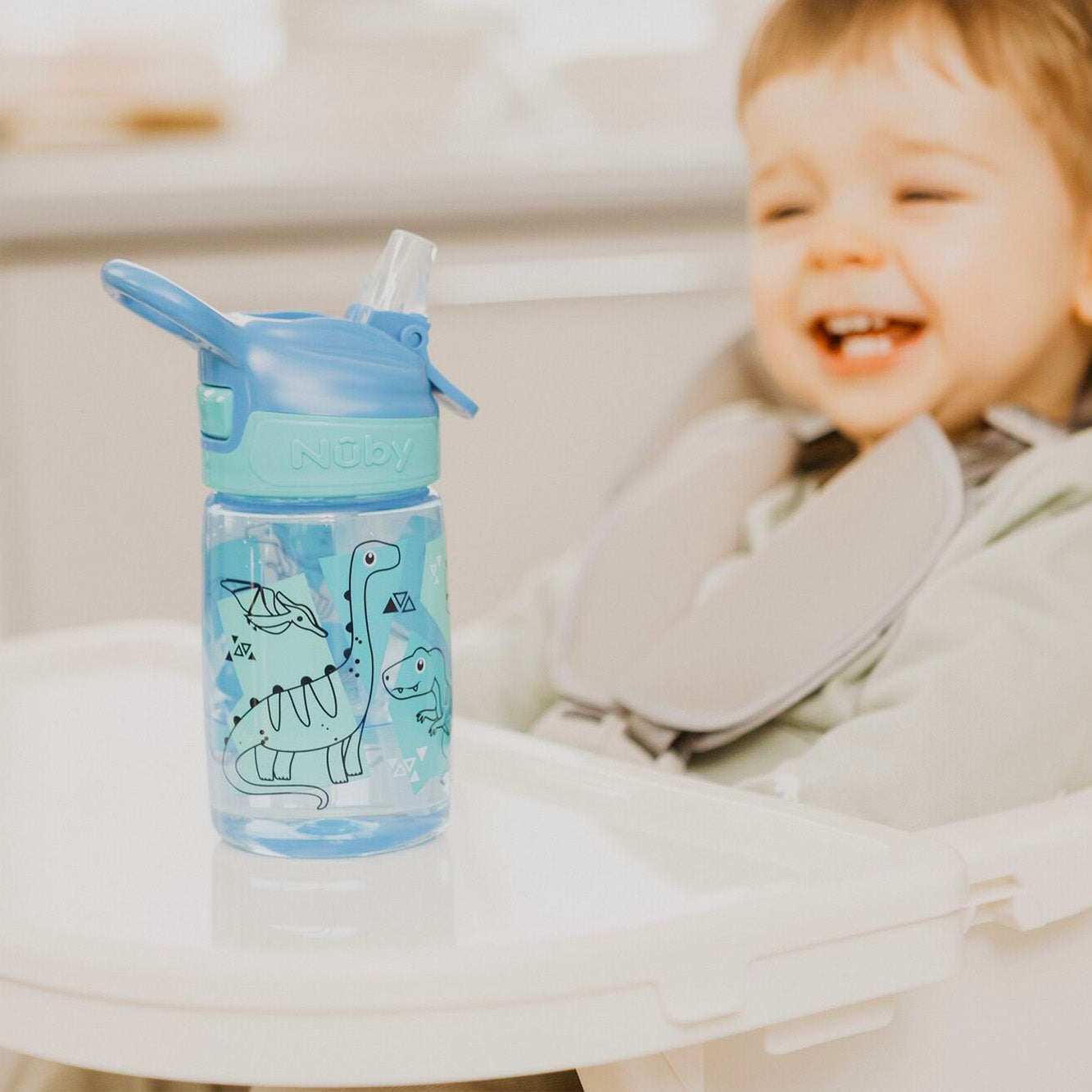 A young child looking at their Incredible Gulp Dinosaur bottle for babies and young children by Nuby.