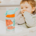 A close up of a young child looking at their Incredible Gulp Strawberry decorated bottle by Nuby.
