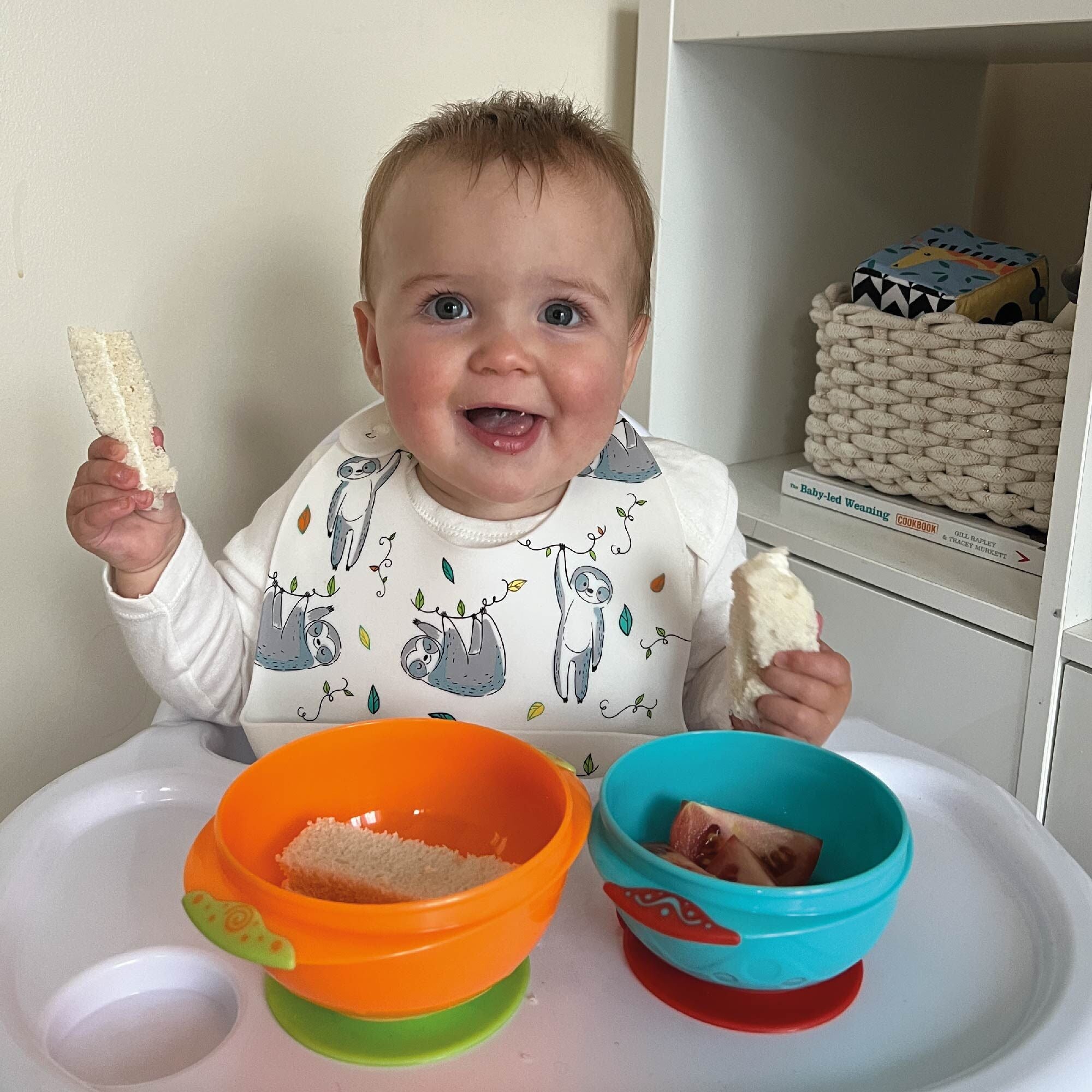 A happy baby enjoying their food from the stackable suction bowls by Nuby.