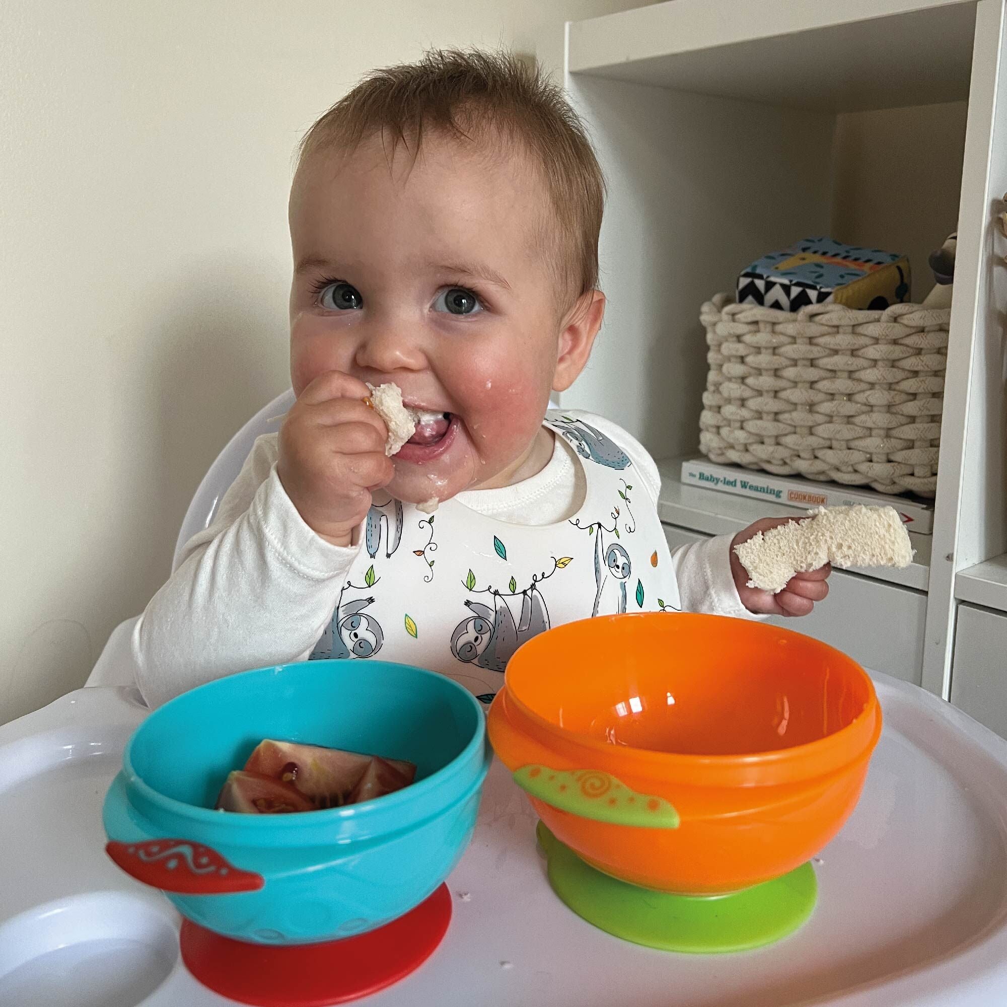 A happy baby enjoying their food from the stackable suction bowls by Nuby.