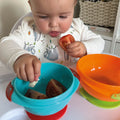 A happy baby enjoying their food from the stackable suction bowls by Nuby. A close up of tomato inside this bowl.