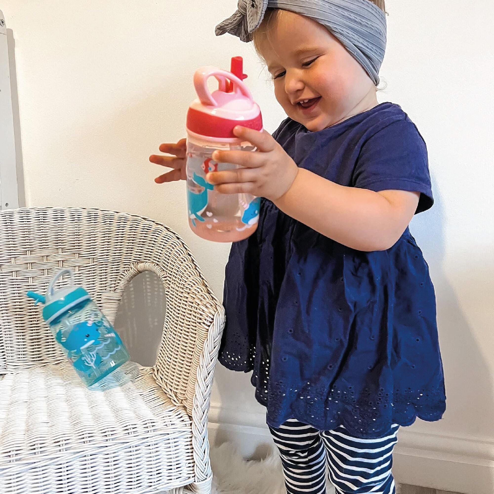 A young child admiring their Mighty Swig bottle that is decorated in whales and nautical themes.