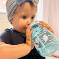 A young child drinking from their Mighty Swig bottle that is decorated in whales and nautical themes.