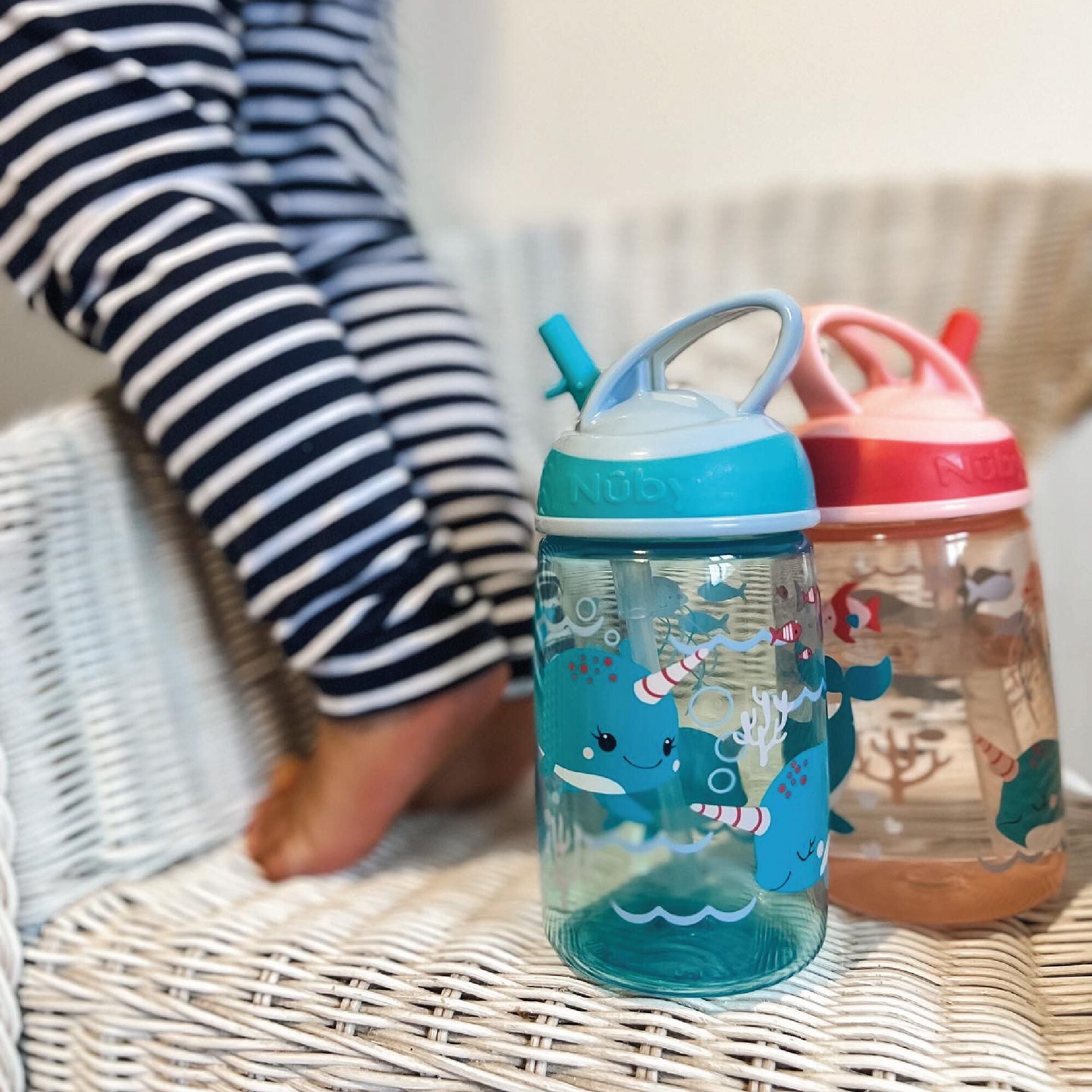 The two Mighty Swig bottles from Nuby decorated in Narwhal, whales and nautical themes as if they are underwater.