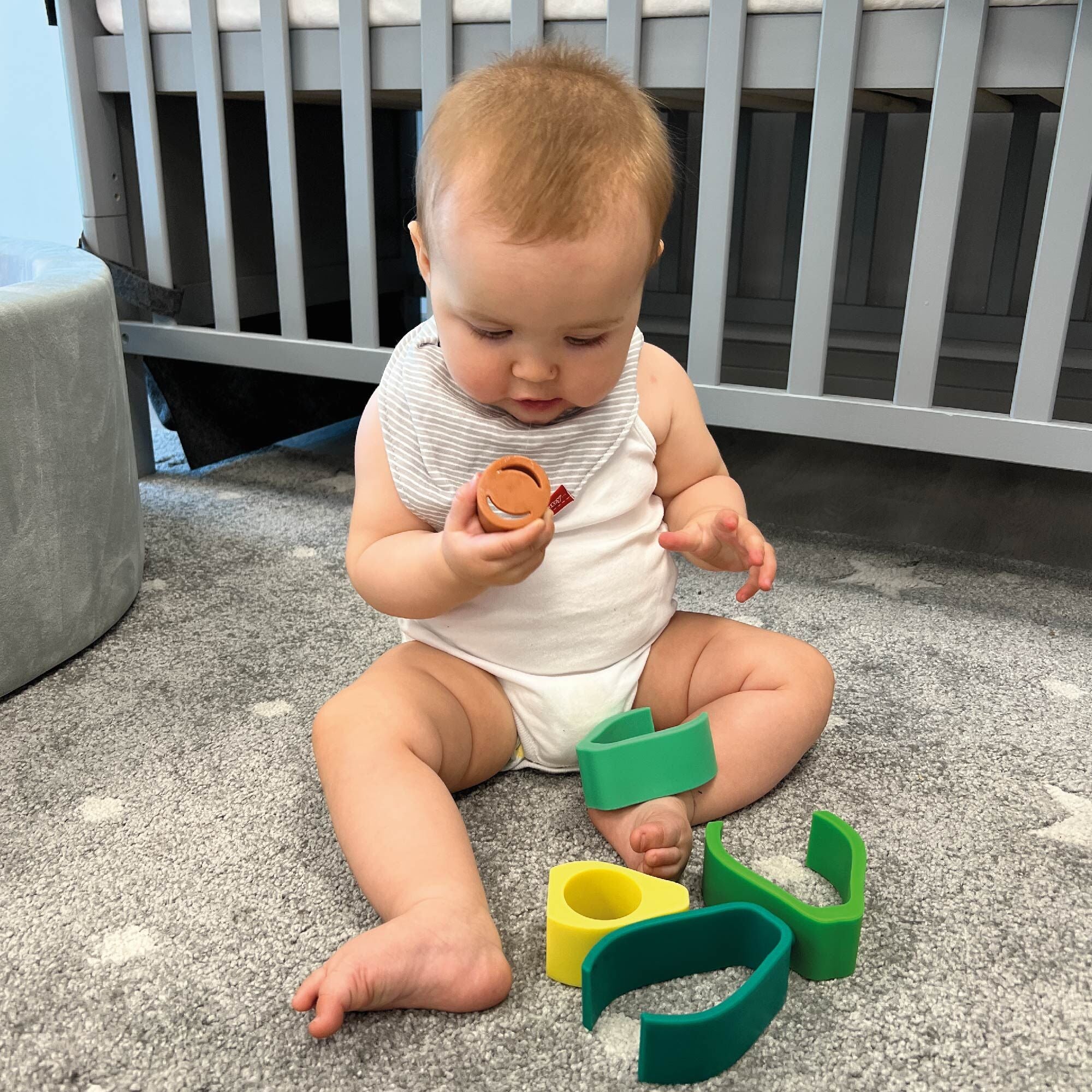 A baby taking a closer look at the Avocado stacking baby toy by Nuby.