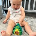 A baby staring at the Avocado Stacking Toy by Nuby.
