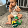A baby putting the Avocado Stacking Toy in their mouth.