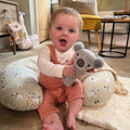 A baby holding the Koala bear from the Animal Adventures gift set by Nuby.