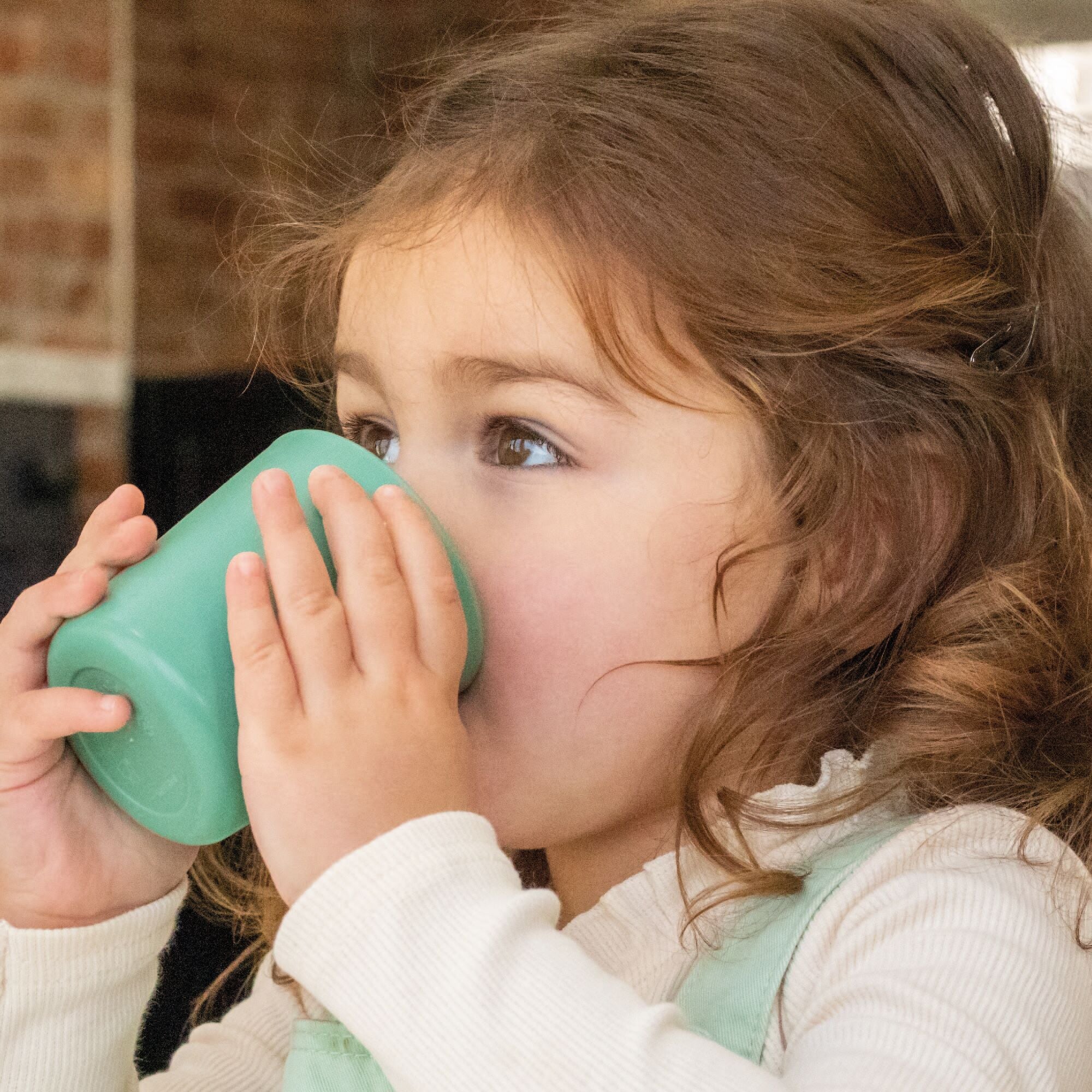 A toddler drinking from a tumbler created by Nuby.