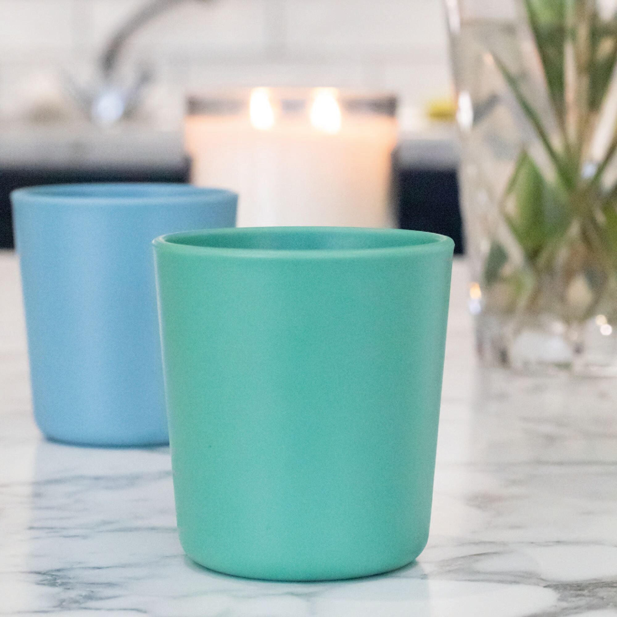 Two tumblers by Nuby sat on top of a table in aqua and blue colours.