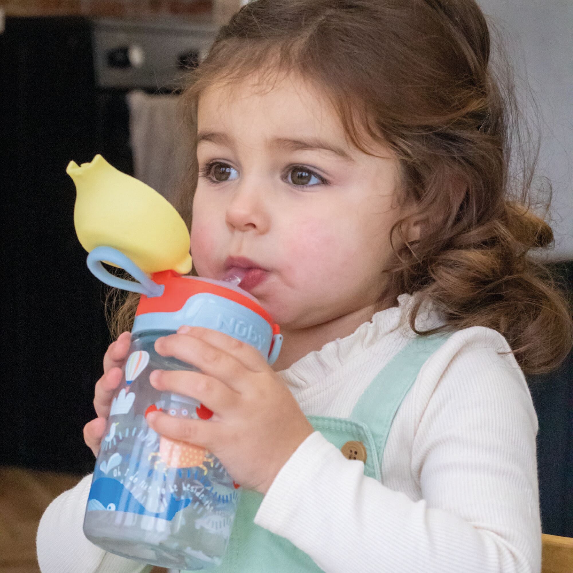 A baby using the Super Straw sippy cup from Nuby.