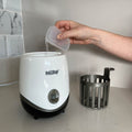 The bottle food warmer on a desktop by Nuby. With liquid being poured onto it.