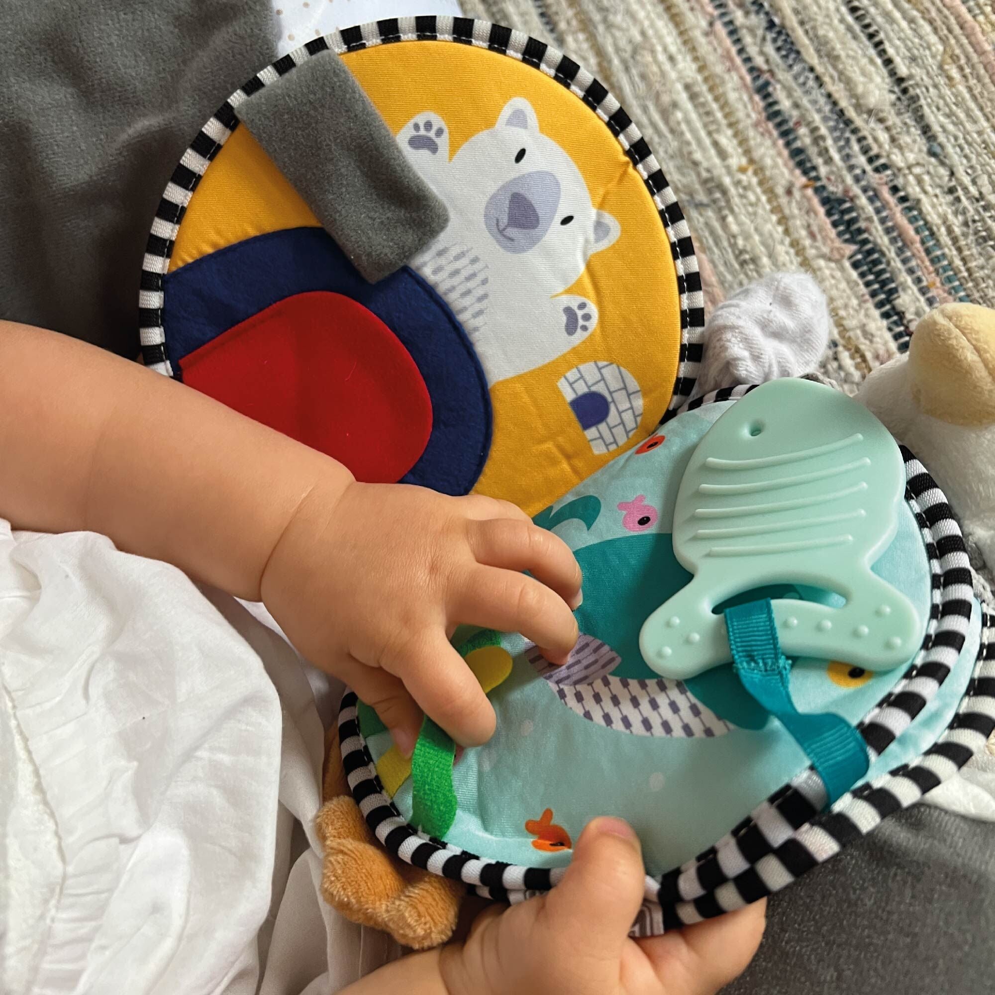 A baby flicking through the pages of the Penguin Soft Touch Book by Nuby.