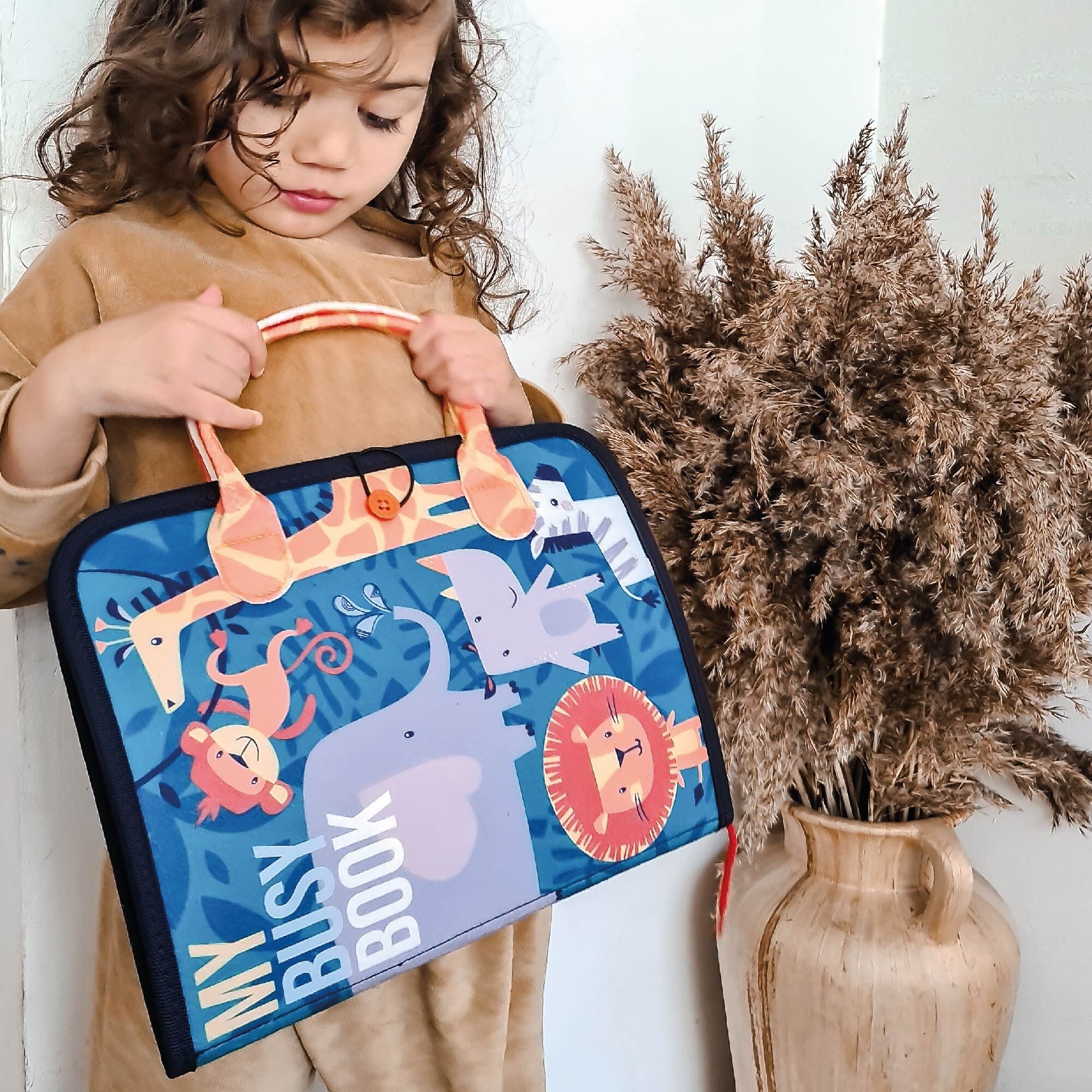 A girl holding her my busy book by Nuby.