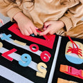 A zipper being played with by a young girl that is using the My Busy Book by Nuby.