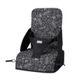 The Nuby Travel Booster Seat features black and white fabric with playful animal, leaf, and sun doodles, safety straps, and side arm supports—perfect for young children on the go.