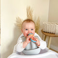 A baby looking happy as they eat from their Nuby Nibbler.