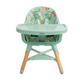 The Nuby UK Highchair Green features mint green color, light wooden legs, a tray, a patterned seat cover with colorful plants and animals, and safety harness straps.