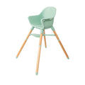 The Nuby UK Highchair Green features a minimalist mint green plastic seat with matching footrest, natural wooden legs, and green-tipped accents for a modern, contemporary look.