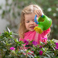 A young girl watering flowers in a garden by using their Nuby Watering Can.