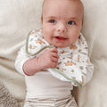 A baby wearing on of Nuby's dry, organic bibs. The baby is wearing the bib that is decorated with different safari animals on the front.