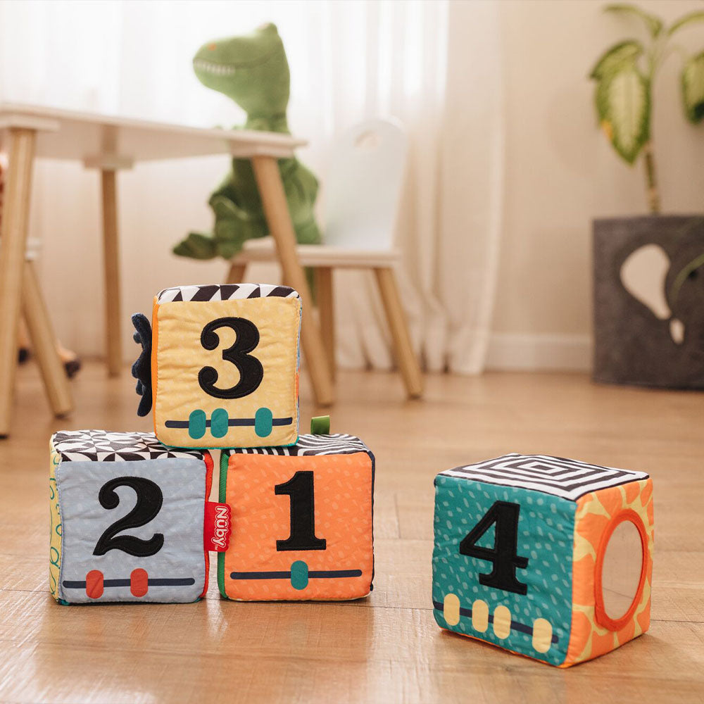 The different numbers that are included in the Little Learner Cubes facing the camera. All laid out on a living room floor.