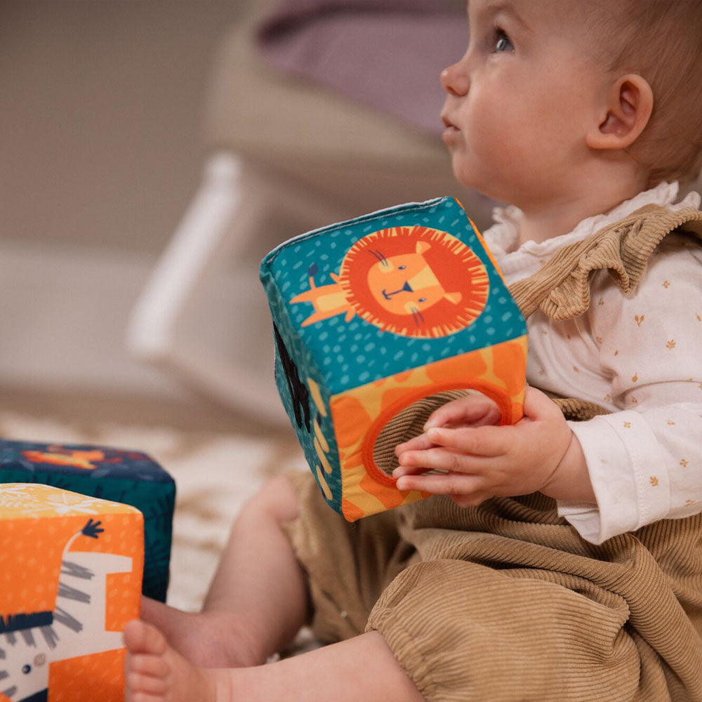 A young child holding the Little Learner Cubes by Nuby.