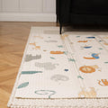 The Nuby Foldable Play Mat, Safari, featuring animal illustrations, is placed on a beige textured rug in the living room, partially under a dark wooden-legged sofa atop a herringbone wood floor.