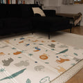 The Nuby Foldable Play Mat, Safari, featuring vibrant animal designs, is laid out on a rug in a cozy living room with a black sofa and shelves in the background.