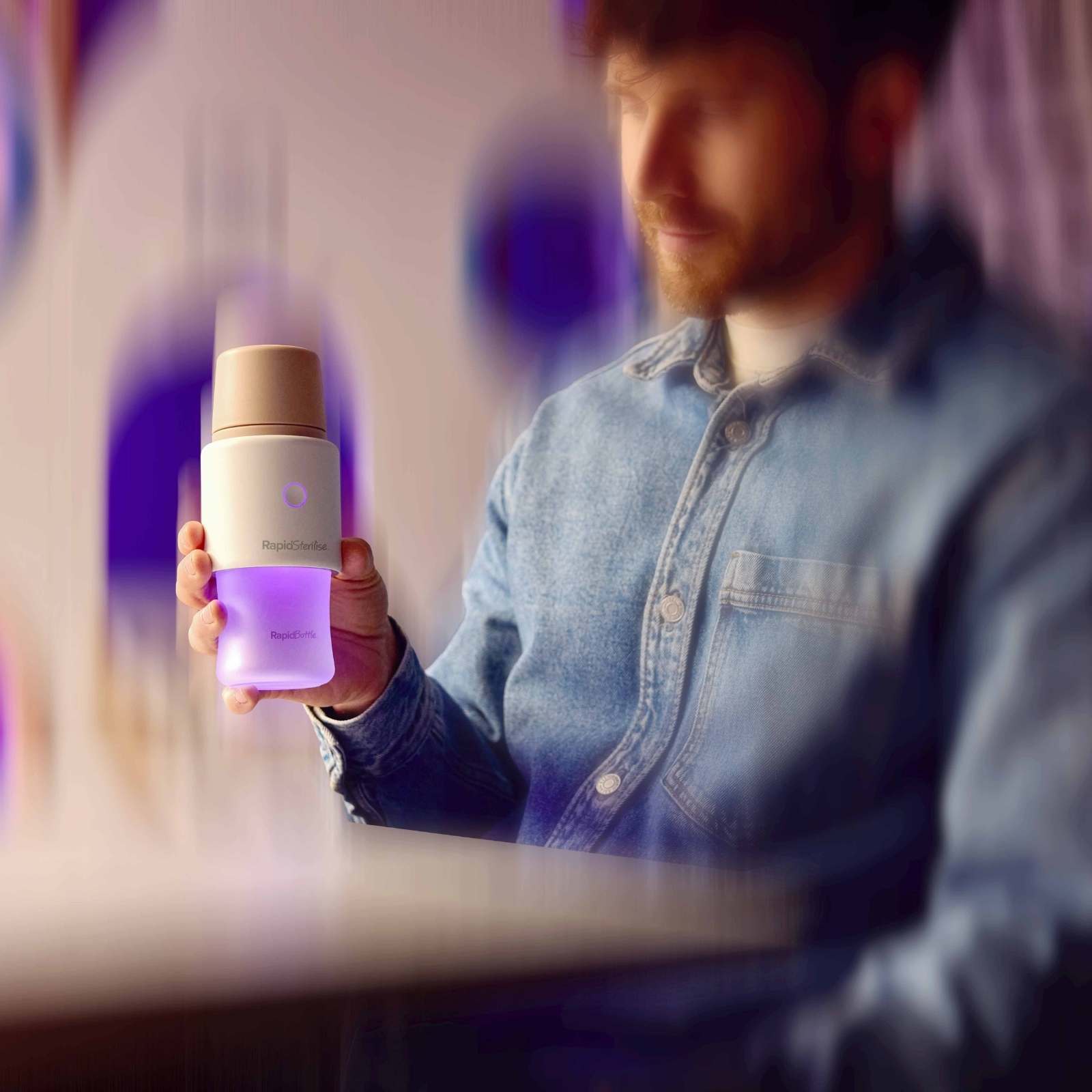 Man holding RapidBottle with  RapidSteriliser+ on, the UV light glowing up the RapidBottle 