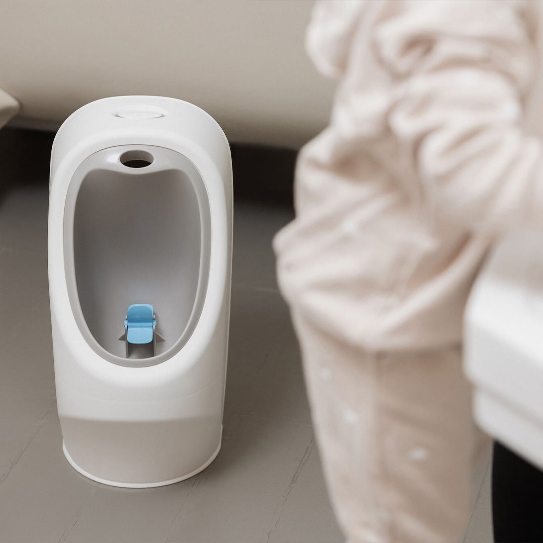 A My Real Urinal stood behind a child washing their hands in a bathroom.