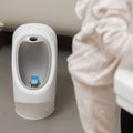 A My Real Urinal stood behind a child washing their hands in a bathroom.