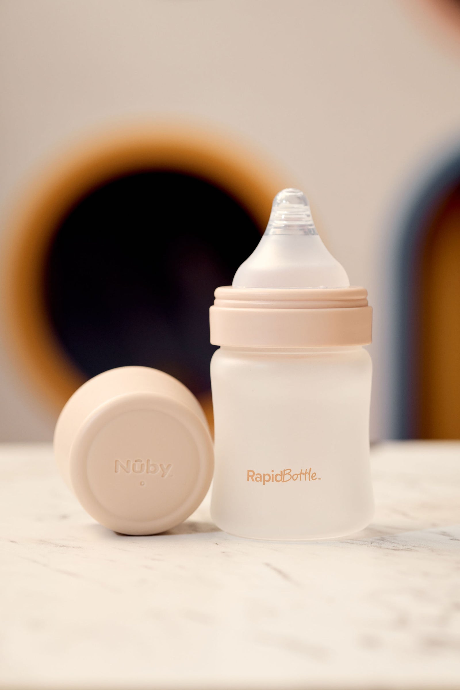 Nuby RapidBottle with the beige lid off showing the triangular shaped anti colic teat.