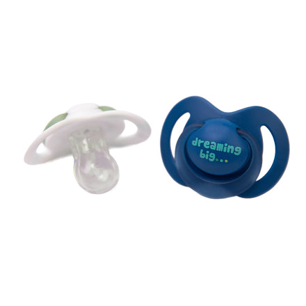 Two Nuby Night Dummies (6-18 months) are shown on a white background: one with a white shield and orthodontic teat, the other with a dark blue glow-in-the-dark shield reading "dreaming big..." in light blue and green.