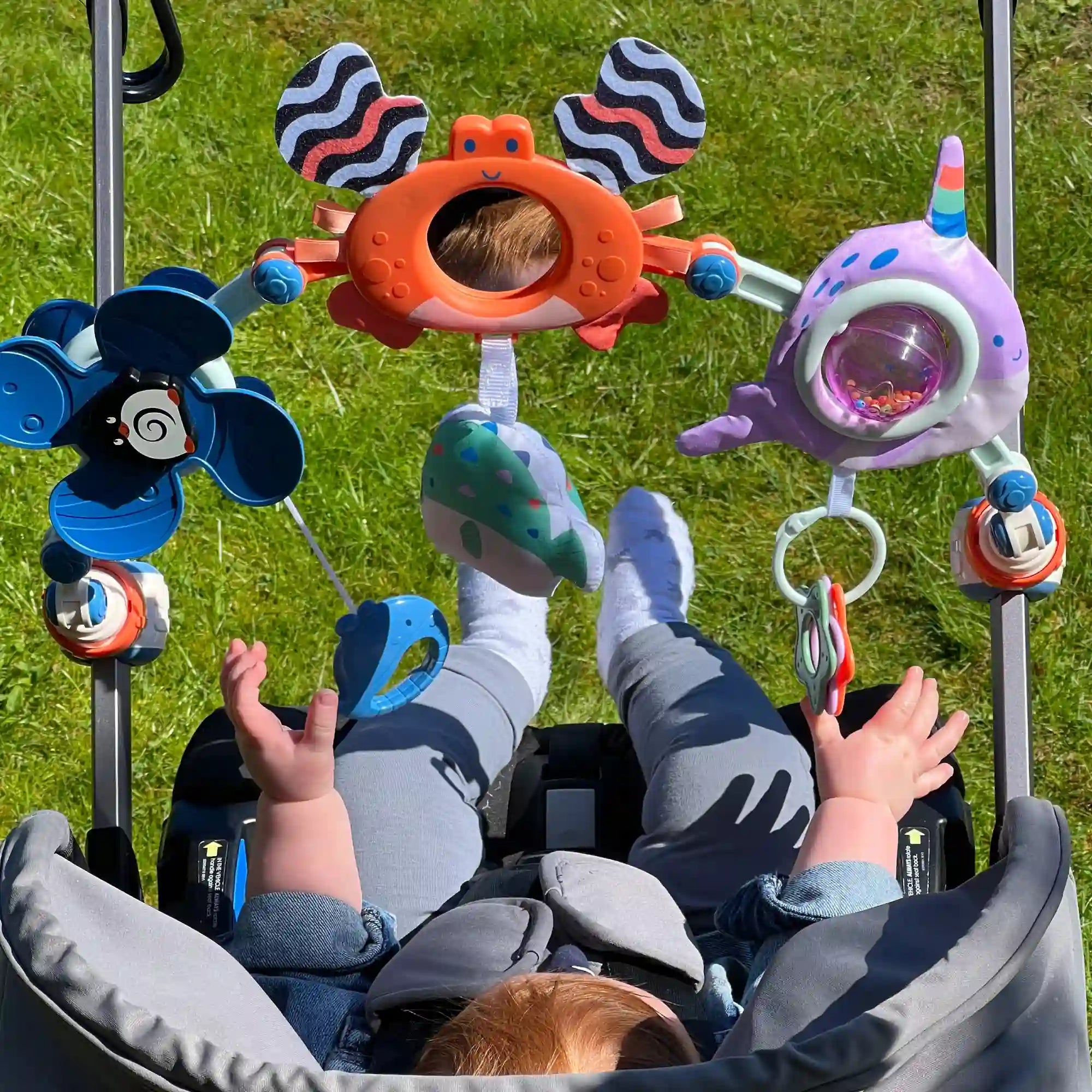 Ocean Friends Pram Toy Arch being played with by a baby. This is a pram product by Nuby.