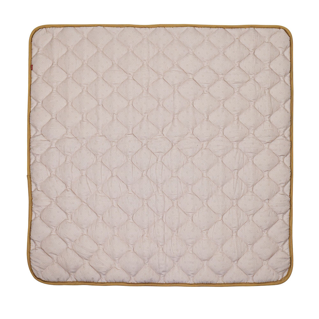 The Quilted Playmat is a beige, padded mat with rounded corners and a brown border, featuring a stitched diamond pattern for added comfort.