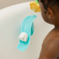 A child enjoys bath time as water flows from the Nuby Splash N Slide Penguin Bath Toy, sending a penguin down a slide and making motor skill development fun and engaging.