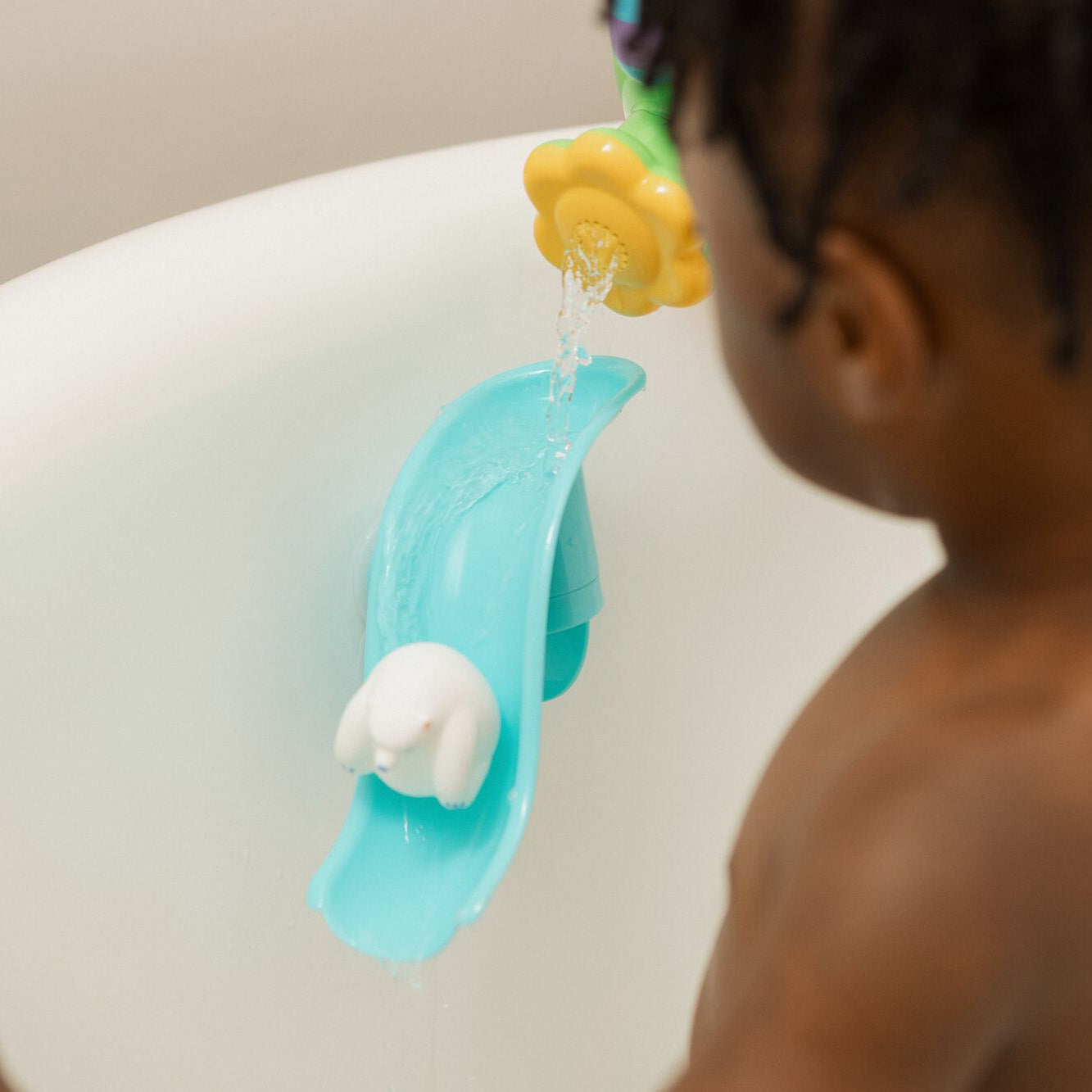 The Penguin bath slide toy from Nuby, with a Polar Bear at the bottom of the slide being played with by a young child in a bath.