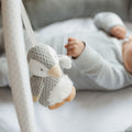 A close up image of the Penguin that is hanging from a play gym created by Nuby, this is with a baby in the background.