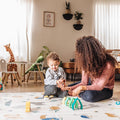 A young child and their mother playing on the Play Mat Safari version by Nuby