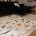 The Nuby Foldable Play Mat, Safari, featuring colorful animal designs, is spread out on the floor of a cozy living room with a dark sofa and neutral rug.