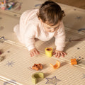 A baby crawling across the Play Mat by Nuby decorated in things that you'd see in the sky including stars, the moon, a shooting star, the sun and so on.